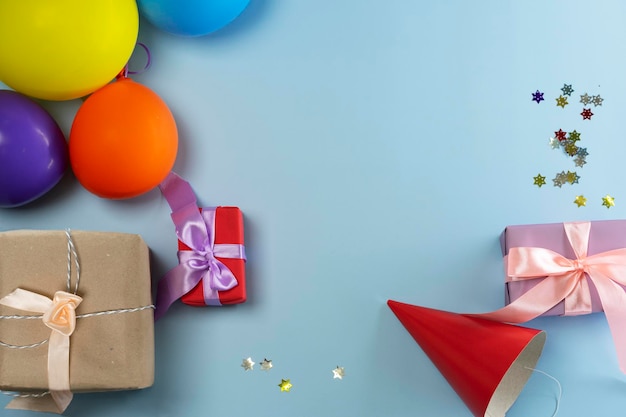 Gifts in wrapping paper, balls, a cap, flowers on a beautiful blue background. View from above.