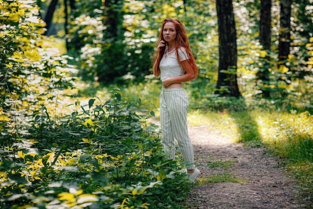 Ginger beautiful woman in casual outfit posing in the forest