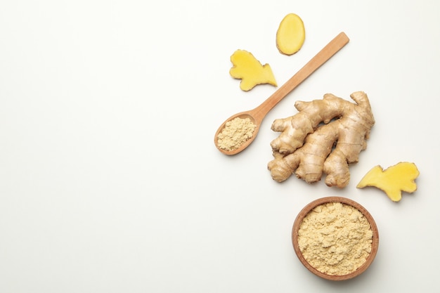 Ginger and bowl with ginger powder on white background