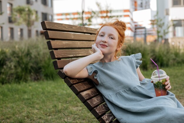 Ginger girl with lemonade in a plastic cup