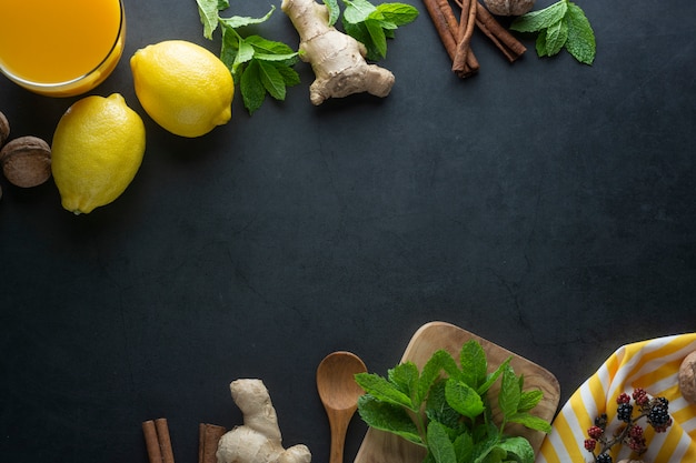 Ginger, lemons and mint leaves on dark surface, 