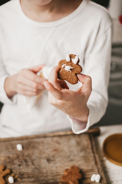 Ginger man in white glaze in the hands of a child, close-up, on a white background. The gingerbread man is bathed in cocoa. Christmas mood. Christmas sweets and drinks, copy space