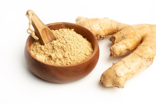 Ginger powder in a wooden bowl and a ginger root on a white background with copy space