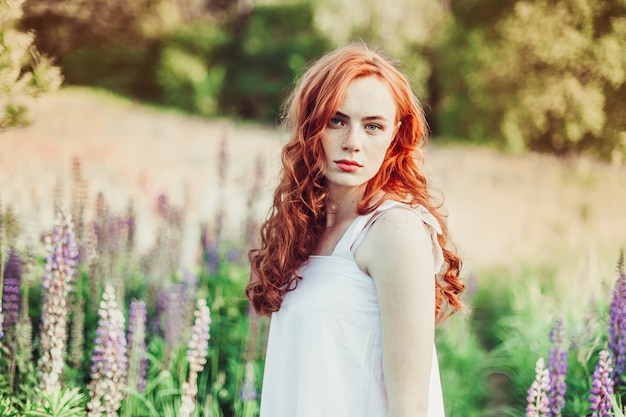 Ginger red headed girl with curly hair in the field