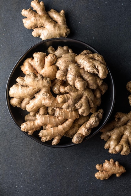 Ginger roots from the garden in plate on black surface