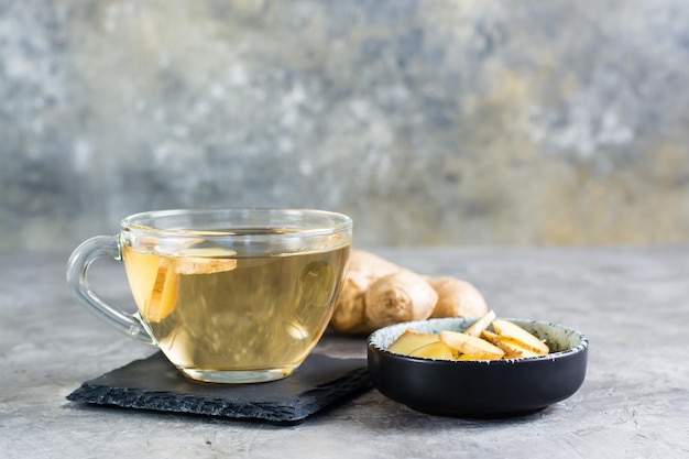 Ginger tea in a cup and chopped root in a bowl on the table Natural Vitamins