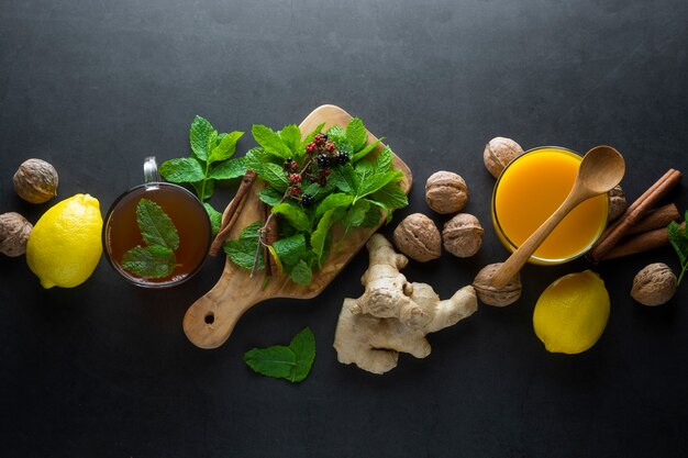 Ginger tea cup with lemons and mint leaves on dark surface,