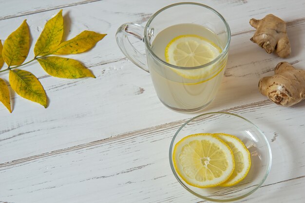 Ginger tea with lemon and leaves on a white table