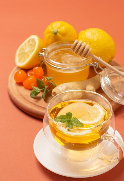 Ginger tea with mint and lemon. Healthy and hot drink. Liquid honey in honey-jar. Crystal cup