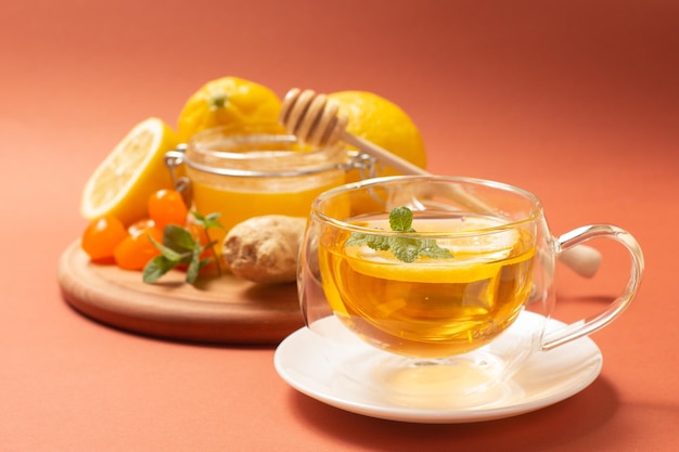 Ginger tea with mint and lemon. Healthy and hot drink. Liquid honey in honey-jar. Crystal cup