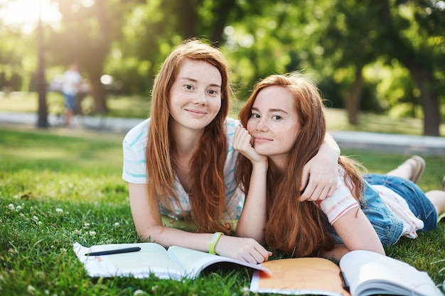 Ginger twins preparing for their exams outdoors in a city park. Learning is so much better with a best friend. Study and knowledge concept.