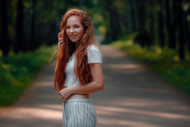 Ginger young beautiful woman posing in a green forest