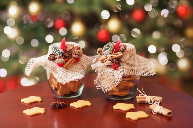 Gingerbread Christmas cookies  in the glass jar.  Christmas spices and decor close up. Festive background with bokeh and light.  New Year and Christmas card. Magic fairy tale