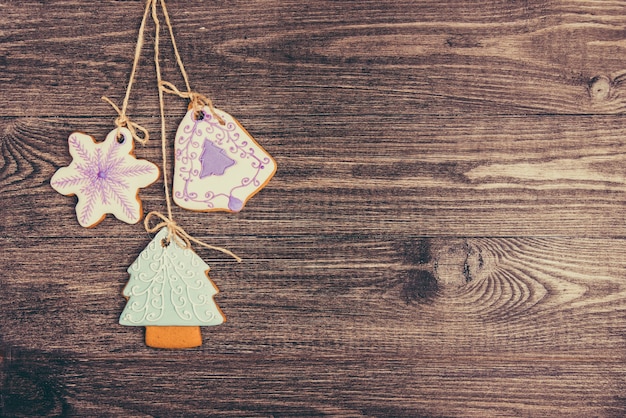 Gingerbread cookies hanging over wooden background. Copy space.