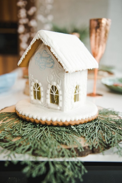 Gingerbread house, concept holiday of Christmas and Happy new year. Homemade gingerbread house with candy windows on a wooden table with Christmas decorations. Holiday mood