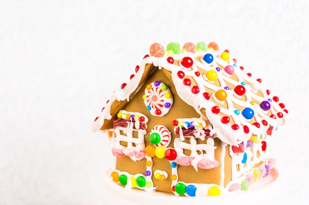 Photo gingerbread house decorated with white royal icing and bright candies.