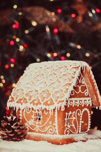 Gingerbread house over defocused lights of Chrismtas decorated fir tree