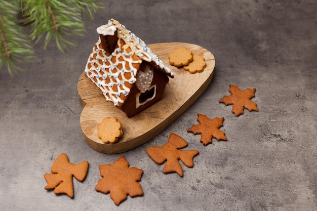 Gingerbread house with cookies Close up shot of sweet home dessert with icing decoration on gray