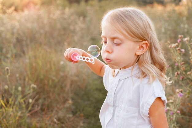 A girl of 5 years old inflates soap bubbles on a walk on the weekend. child protection