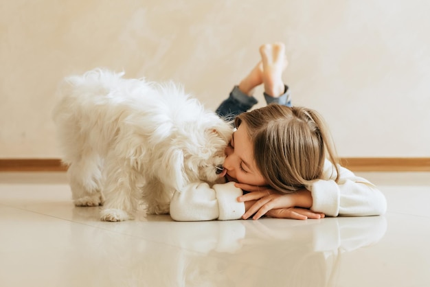 girl 9 years old with long hair model with a pet dog Maltese schoolgirl at home lifestyle