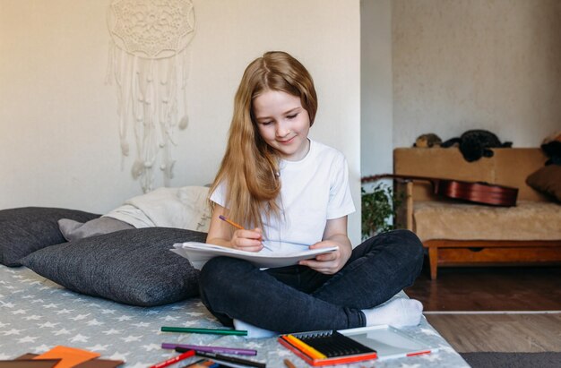 The girl after school plays at home draws with pencils and felt-tip pens