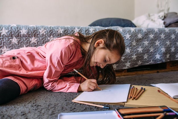 The girl after school plays at home draws with pencils and felttip pens