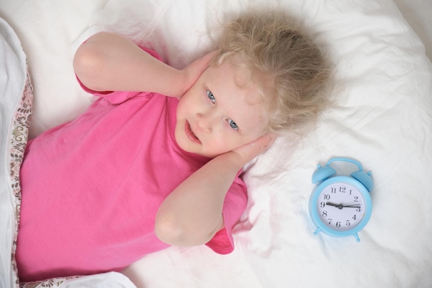 Girl and alarm clock on the bed