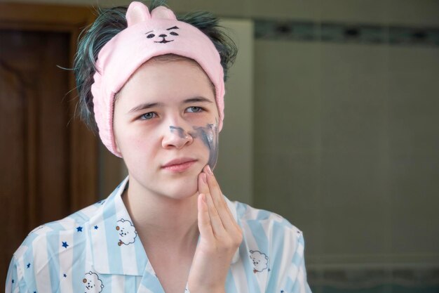 Photo the girl applies a cleansing cosmetic mask to her face. skin care. healthy lifestyle.