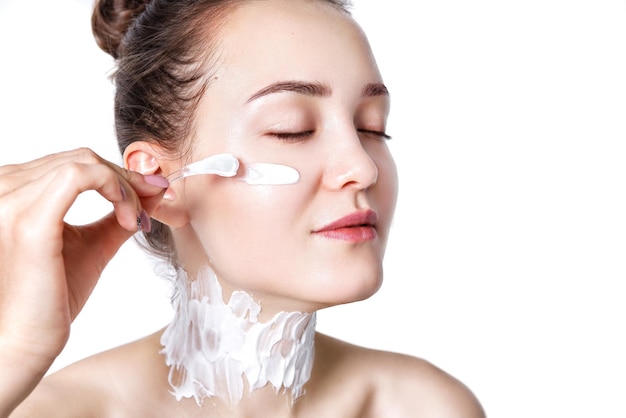 The girl applies a thick face and neck cream to cleansed skin