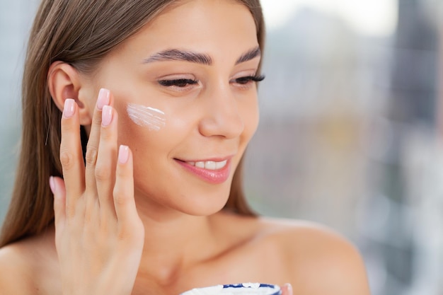 Girl applying moisturizing cream on her face