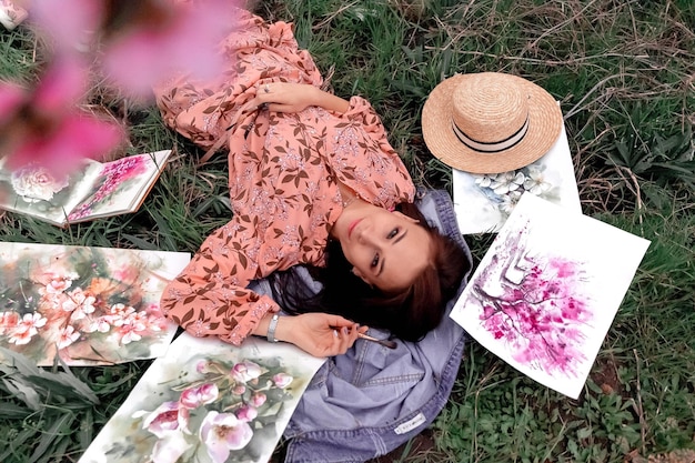 Girl artist paints a peach orchard in a peach orchard spring