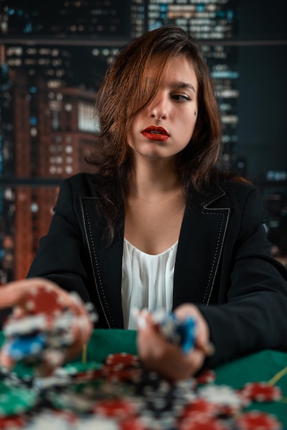 Girl as a poker player with a lot of colored chips at a round green table casino poker concept woman