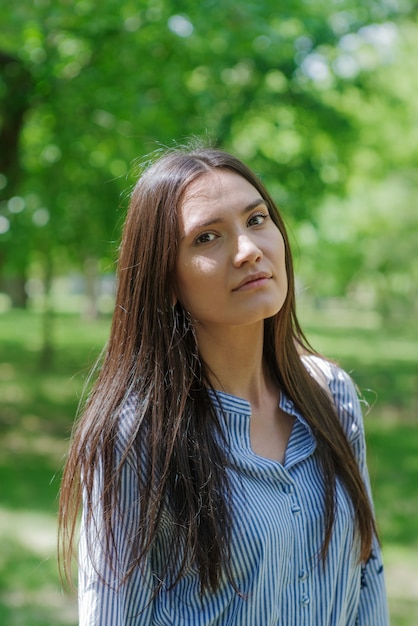 girl of asian appearance in city park summer portrait of young tatar on background of green foliage