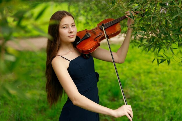 A girl of Asian appearance plays the violin in nature. High quality photo