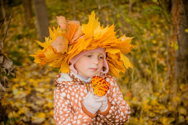 girl in autumn golden park with a wreath of leaves.