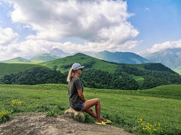 A girl on the background of a green landscape of the Aktoprak pass in the Caucasus Russia June 2021