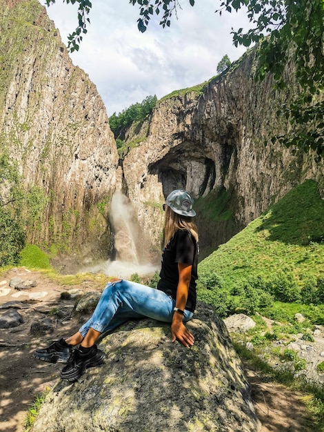 A girl on the background of the KarakayaSu waterfall on the territory of KabardinoBalkaria