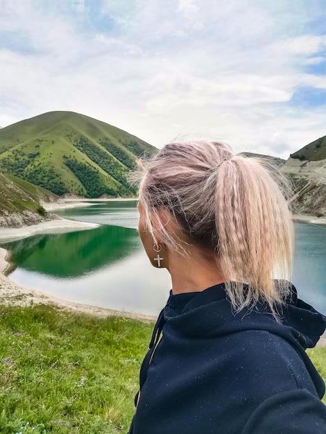 A girl on the background of Lake Kezenoyam in the Caucasus mountains in Chechnya Russia June 2021