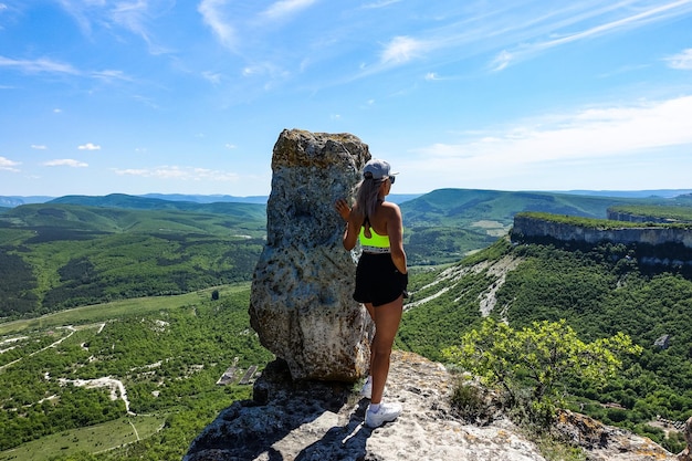 A girl on the background of a view of the Crimean mountains from the cave city of TepeKermen May 2021 Crimea Russia