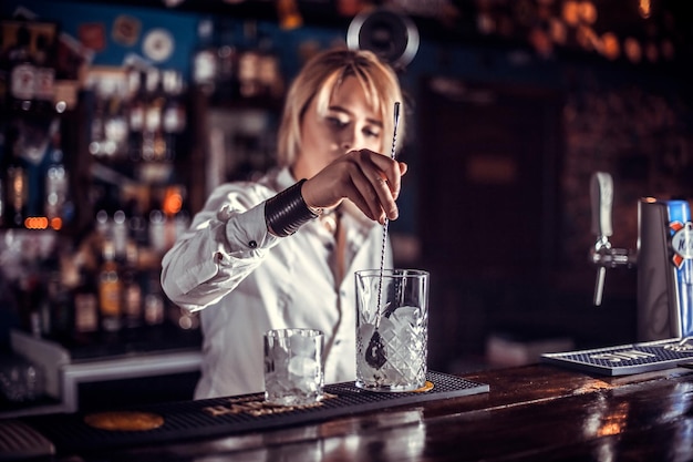 Girl barman formulates a cocktail on the beerhouse