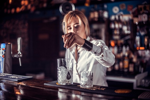 Girl barman formulates a cocktail on the beerhouse