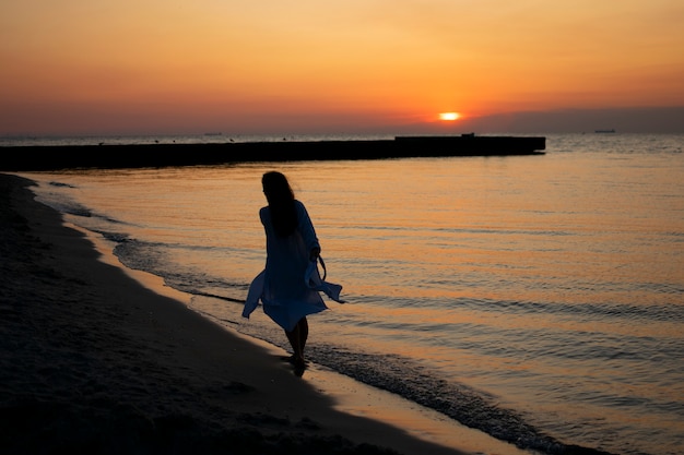 The girl on the beach meets dawn, runs on the sand.