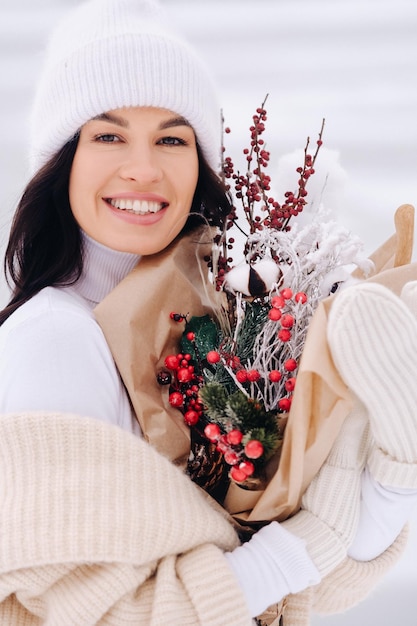 A girl in a beige cardigan and winter flowers walks in nature in the snowy season Winter weather