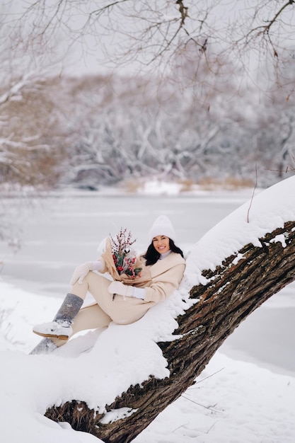 A girl in a beige cardigan and winter flowers walks in nature in the snowy season Winter weather