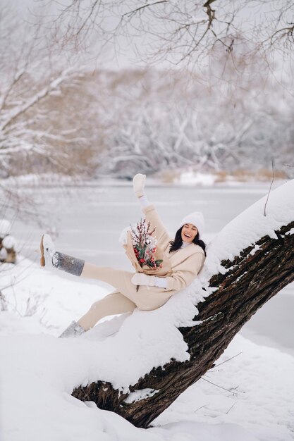 A girl in a beige cardigan and winter flowers walks in nature in the snowy season Winter weather