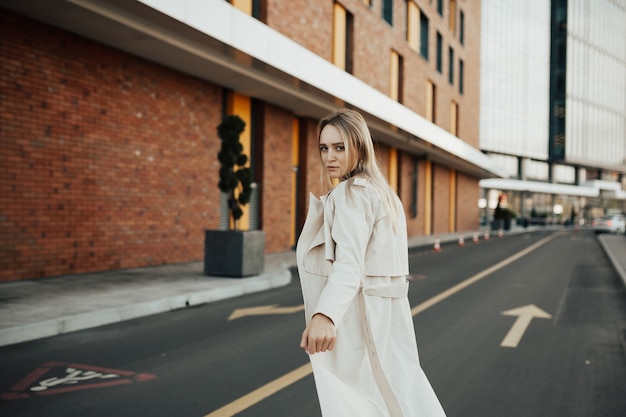 Girl in a beige trench coat on a road.