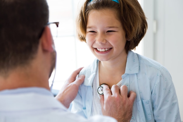 Girl being examined with stethoscope by pediatrician in the office.