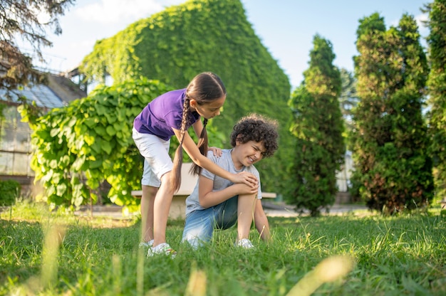 Girl bending over to boy sitting on grass