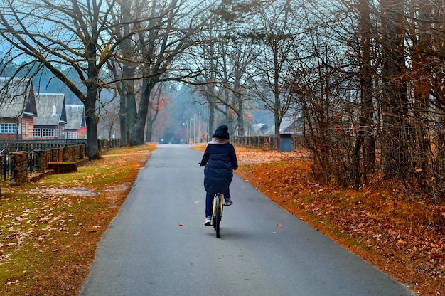 Girl on bicycle rides in autumn foggy village