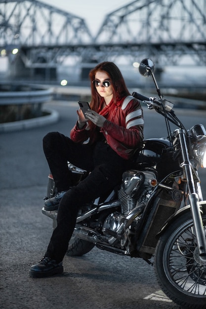 Girl biker sexually posing on motorcycle at night city